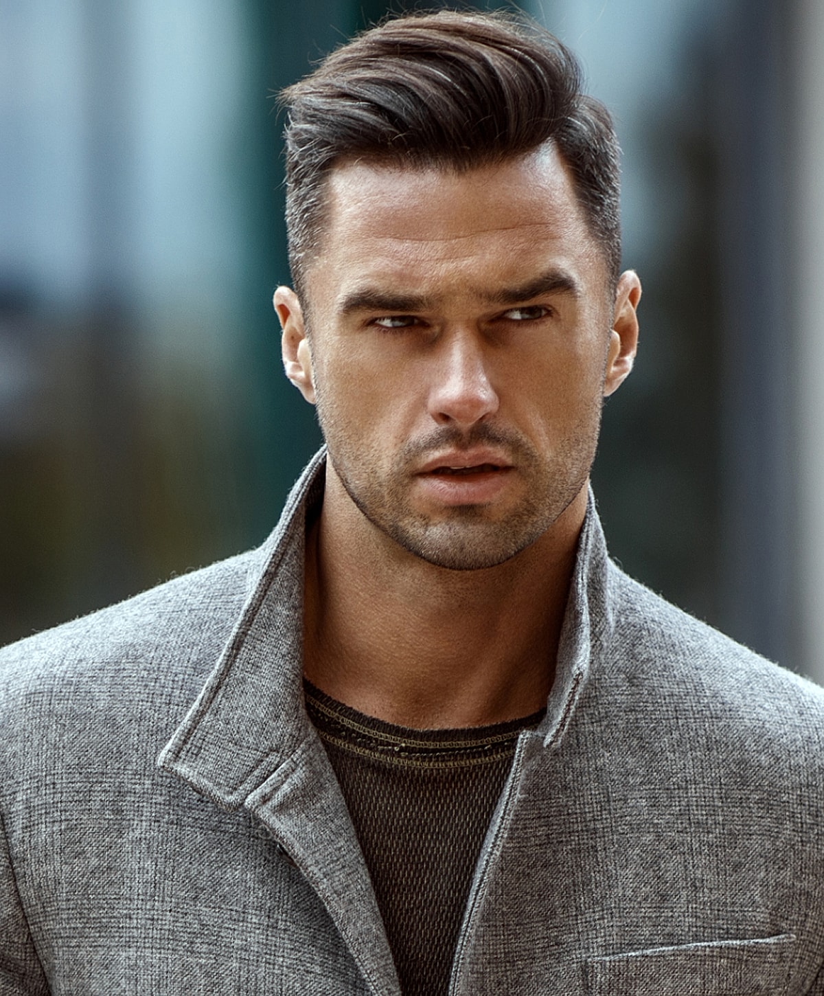 Man in stylish gray coat looking serious.