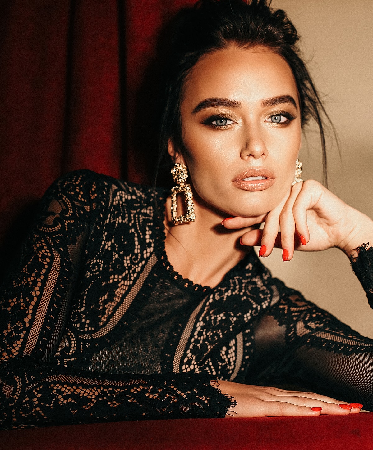 Woman in elegant black lace outfit and earrings.
